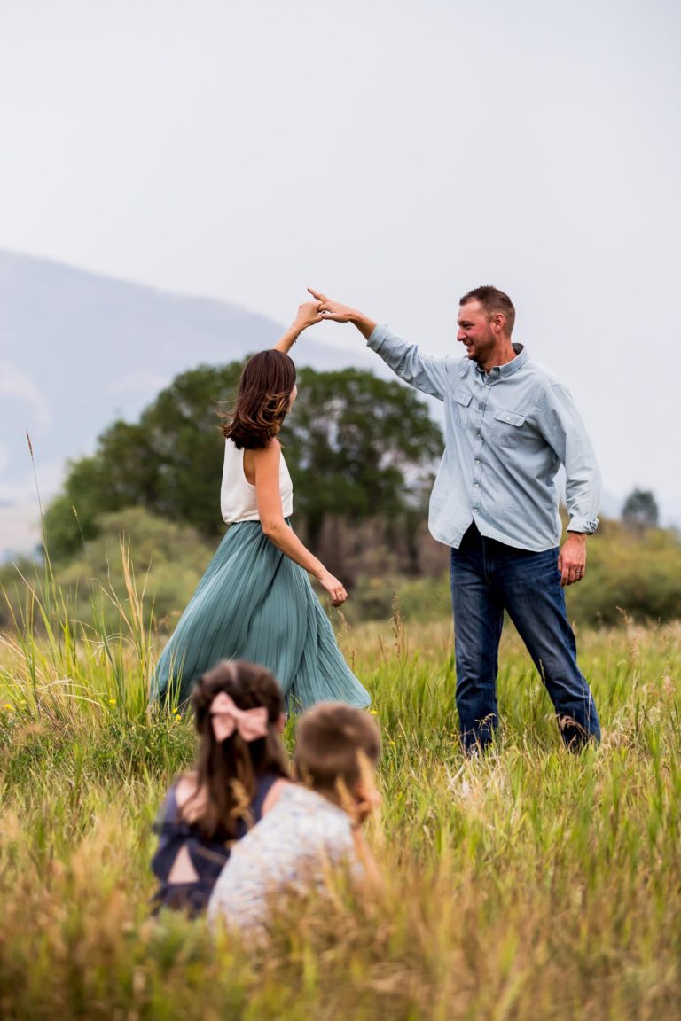 family portrait photography of a husband and wife smiling in a field