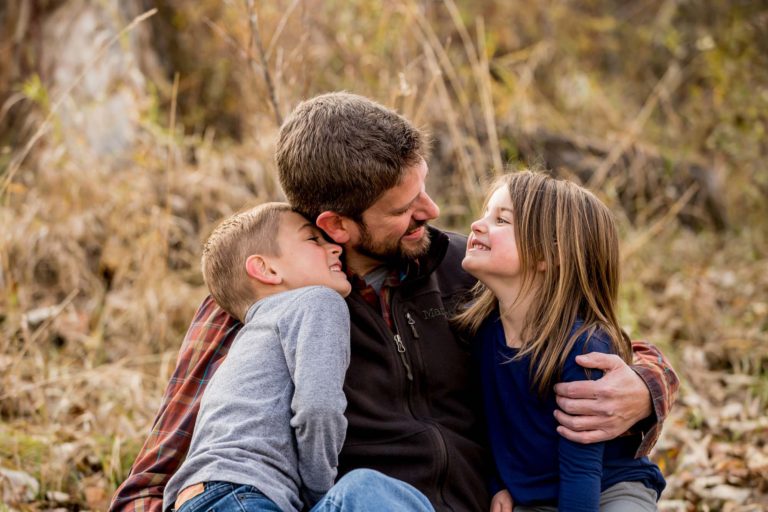 family portrait photography of a mother, father, and teenage daughter walking hand in hand through a field