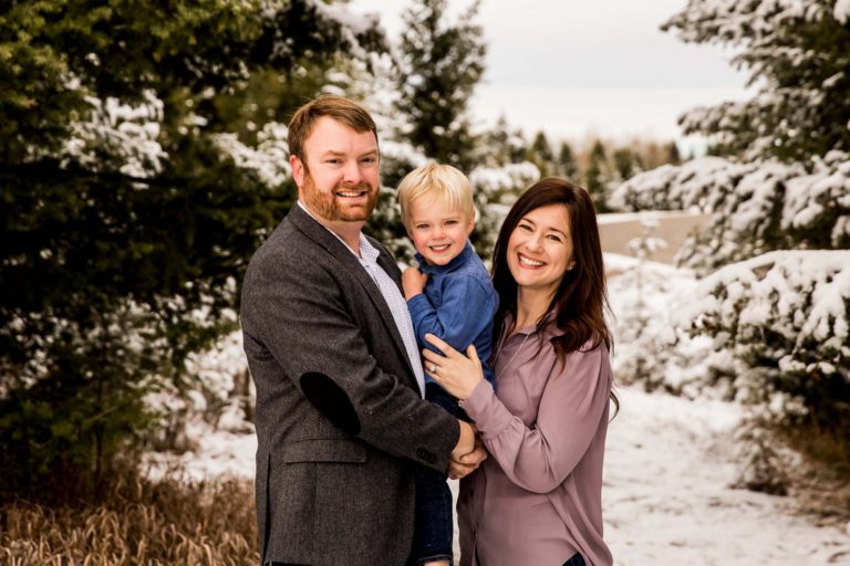 family portrait photography of a mother, father, and teenage daughter walking hand in hand through a field