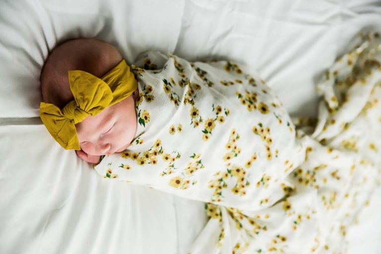 newborn photography of a newborn baby girl sleeping swaddled in a teal blanket