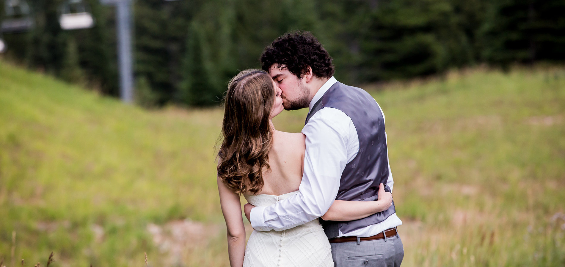 wedding photography of bride and groom kissing outside near mountains after the ceremony