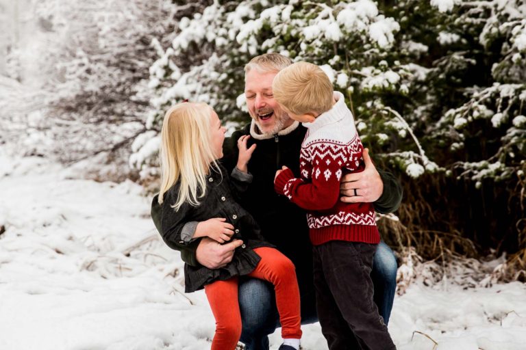 family portrait photography of a young boy smiling wide with his eyes closed outside