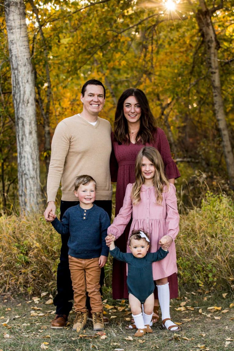 family portrait photography of a mother, father, and teenage daughter walking hand in hand through a field