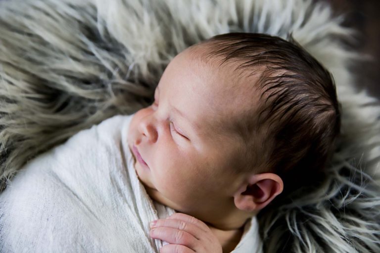 newborn photography of a new father smiling down at his newborn baby yawning in his arms