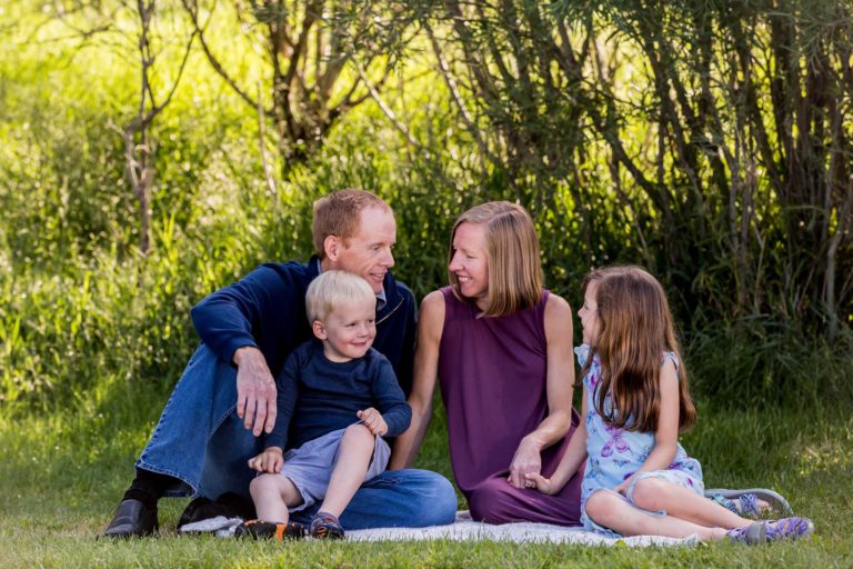 family of four sitting on blanket at the East Gallatin Rec area in Bozeman