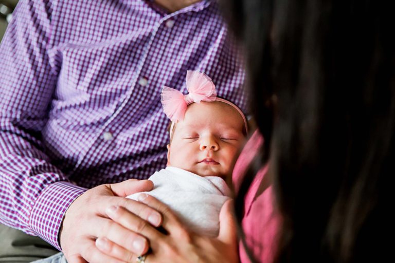 newborn photography of a new father smiling down at his newborn baby yawning in his arms