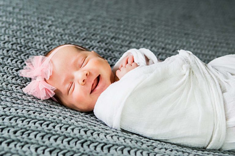 newborn photography of a newborn baby's feet laying on a fluffy grey blanket